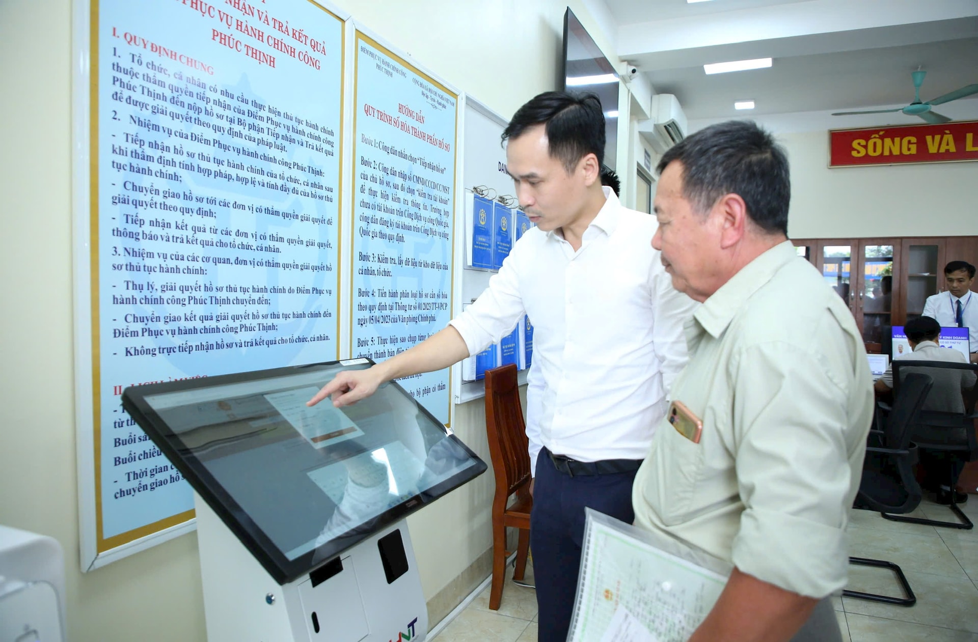 Cán bộ hướng dẫn người dân thực hiện thủ tục hành chính tại điểm phục vụ hành chính công